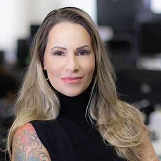 COO Andrea Cianella, ela &eacute; uma mulher branca e loira, com cabelos lisos e longos. Est&aacute; sorrindo e vestindo uma blusa de gola alta preta.