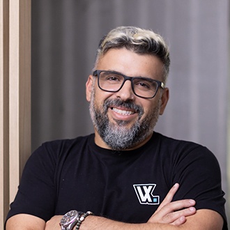 Gestor de Cria&ccedil;&atilde;o Produtos Globo Daniel Chevrand, ele &eacute; um homem branco, com barba, bigode, cabelo curto e grisalho. Est&aacute; usando &oacute;culos, sorrindo, com os bra&ccedil;os cruzados e vestindo uma camiseta preta da VX.