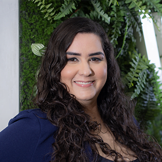 Diretora Executiva Vanessa Gon&ccedil;alves, ela &eacute; uma mulher branca, de cabelo ondulado, longo e preto. Est&aacute; sorrindo e vestindo um blazer azul e uma blusa preta.